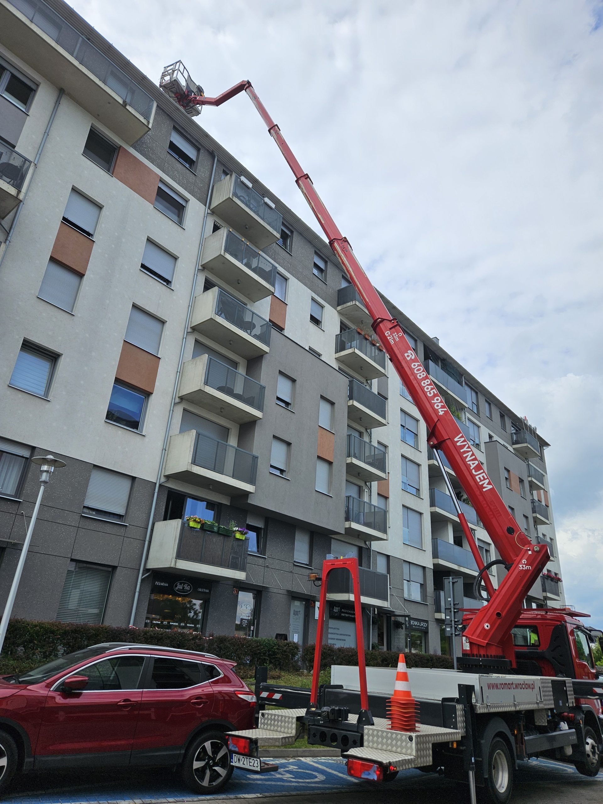 Prace elewacyjne z kosza podnośnika 33m na wysokości 10. piętra.